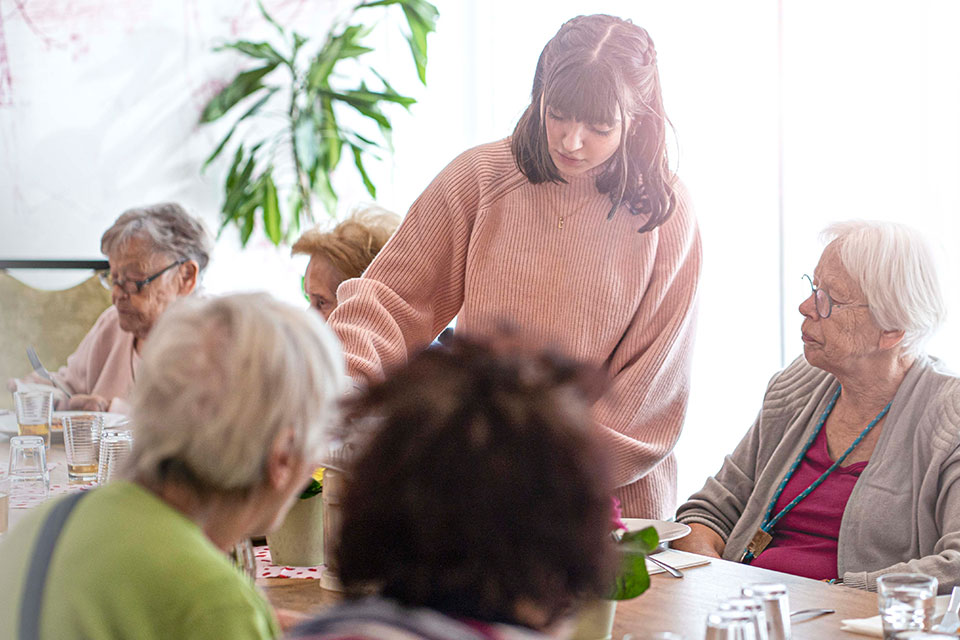 Pflegebewohner am Essenstisch mit Pflegerin
