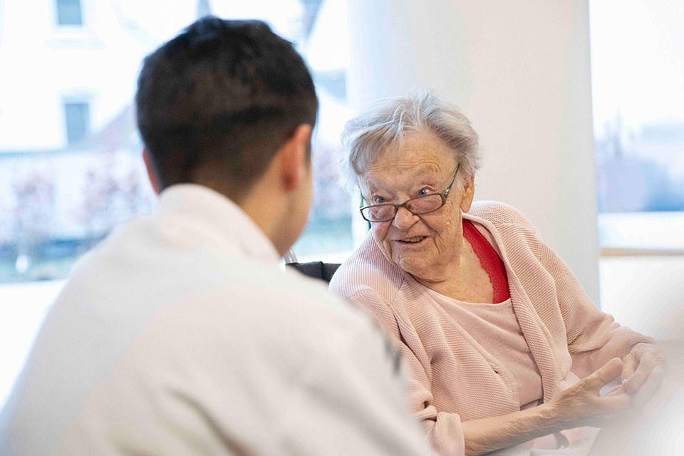 Bewohnerin eines Pflegeheims schaut Pfleger an